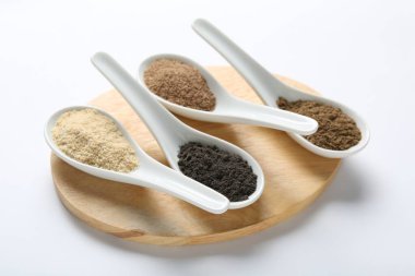 Beyaz arka planda kaşıklarda farklı süper yiyecek tozları, yakın plan