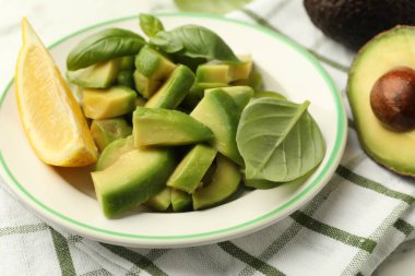 Lezzetli yeşil avokadolar, fesleğen ve limon masada, yakın plan.