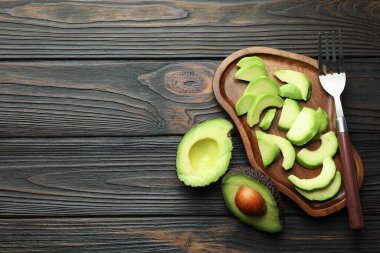 Olgun yeşil avokado ve çatalı tahta masada düz bir şekilde kes. Metin için boşluk