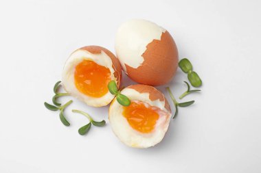 Beyaz arka planda mikro yeşillikli yumuşak haşlanmış yumurtalar, üst manzara.