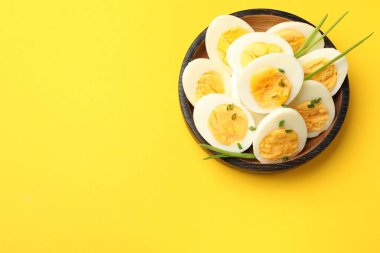 Sarı arka planda yeşil soğanlı haşlanmış yumurtalar, üst manzara. Metin için boşluk