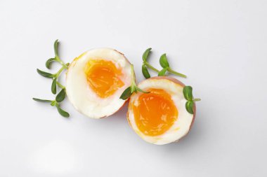Beyaz arka planda mikro yeşillikli yumuşak haşlanmış yumurtalar, üst manzara.