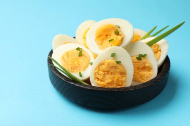 Açık mavi arkaplanda yeşil soğanlı haşlanmış yumurtalar, yakın plan.