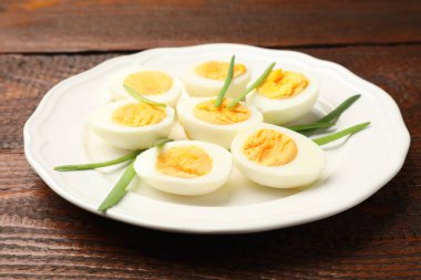 Haşlanmış yumurta ve ahşap masada yeşil soğan, yakın plan.