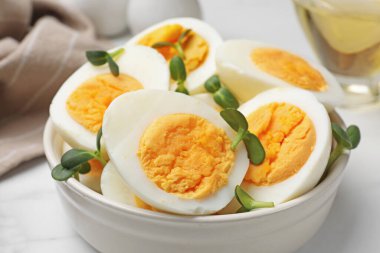 Beyaz masadaki mikro yeşilliklerle haşlanmış yumurtalar, yakın plan.