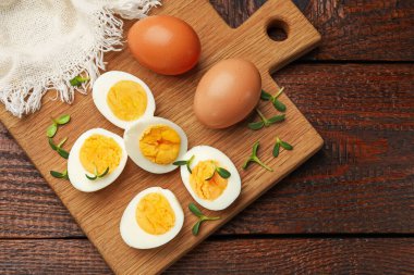 Haşlanmış yumurtaların yarısı ve ahşap masanın üstünde mikroyeşiller.
