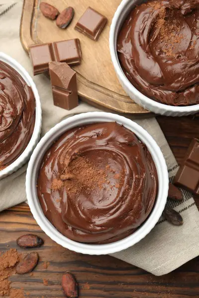 Tabaklardaki lezzetli pudingler, çikolata parçaları ve kakao çekirdekleri ahşap masada, düz yatıyordu.