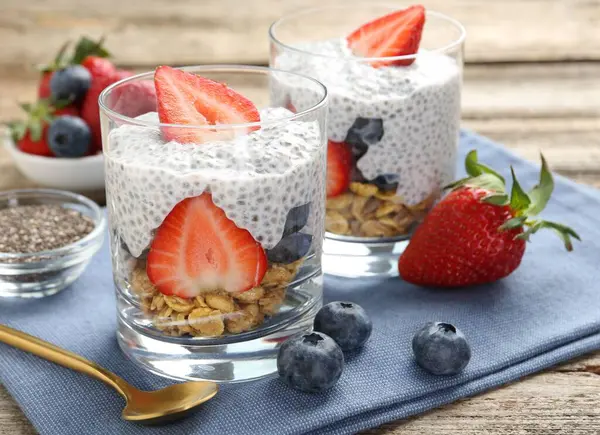 Chia tohumlu lezzetli tatlı, yoğurt, granola, çilek ve böğürtlen ahşap masada, yakın plan. Süper yemek.