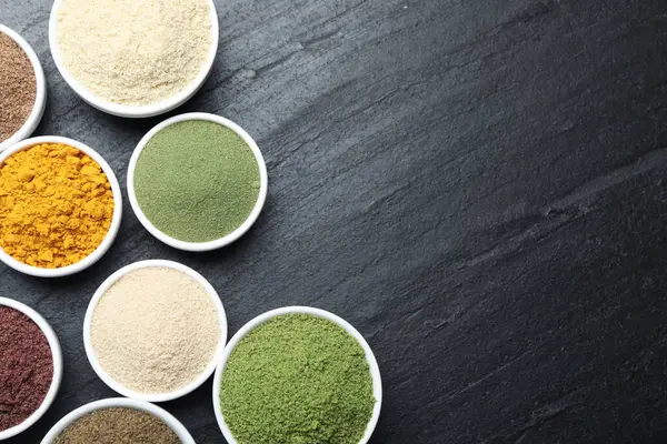 Siyah masanın üzerinde farklı süper yiyecek tozları var. Metin için boşluk