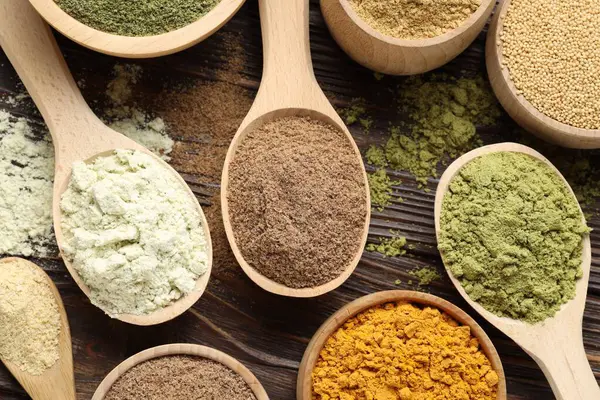 Tahta masanın üzerinde farklı süper yiyecek tozları var.