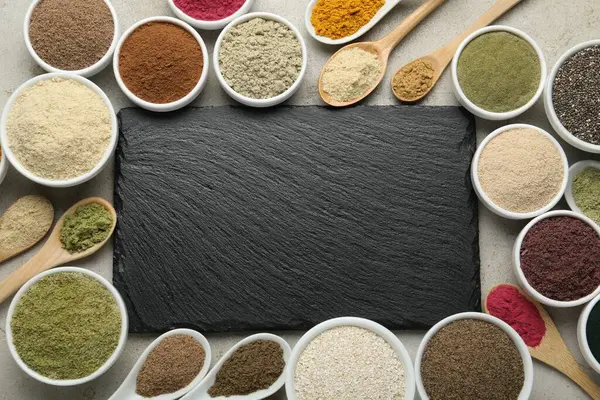 Farklı süper yiyecek tozları ve gri desenli masa, düz yatak tahtası. Metin için boşluk