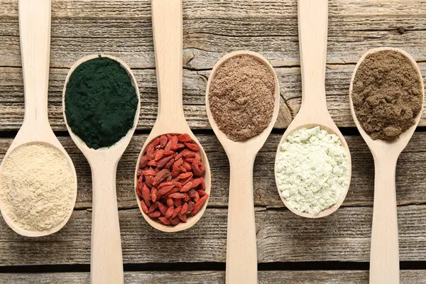 Tahta masadaki kaşıklardaki farklı süper yiyecekler.