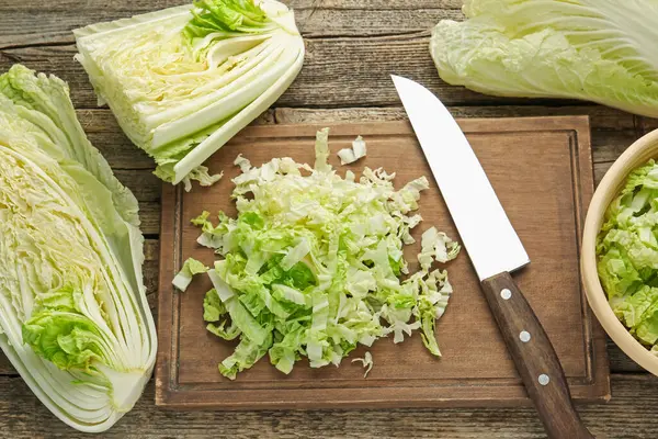 Çin lahanaları ve bıçakları ahşap masada düz bir şekilde yatıyordu.