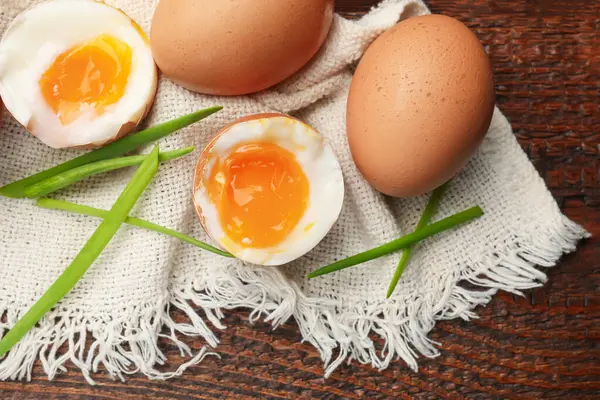 Ahşap masada yeşil soğanlı kaynamış yumurta, düz.
