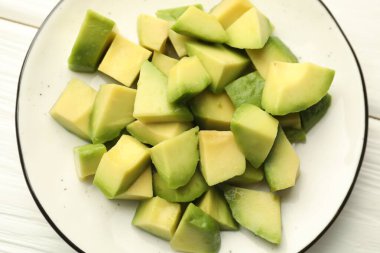 Beyaz ahşap masa üzerinde leziz kesilmiş avokadolar.