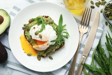 Avokadolu lezzetli sandviç, haşlanmış yumurta, roka ve balkabağı masada servis edilir.