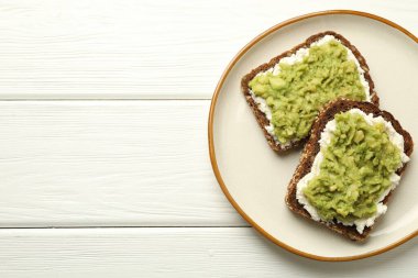 Beyaz ahşap masada avokado ve krem peynirli lezzetli sandviçler. Metin için boşluk