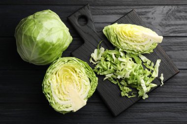 Taze bir bütün ve siyah ahşap masa üzerinde kesilmiş lahana, düz yatıyordu.