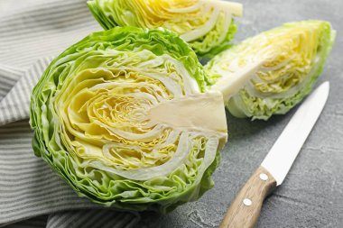 Gri masada taze lahana ve bıçak parçaları, yakın plan.