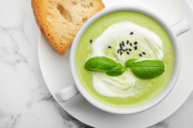 Fesleğenli bezelye kremalı çorba beyaz mermer masada servis edilir.