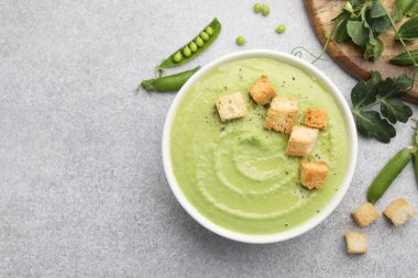 Gri masada servis edilen kıtır ekmekli bezelye kremalı çorba.