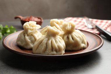 Gri masadaki sosla servis edilen lezzetli khinkali, yakın plan.