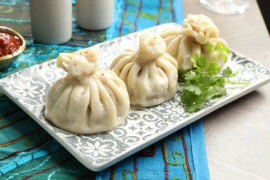 Gri masada soslu kişniş ve kişniş ile servis edilen lezzetli khinkali, yakın plan.