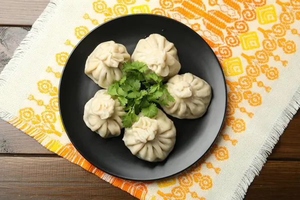 Ahşap masada kişniş ile servis edilen nefis khinkali, üst manzara.