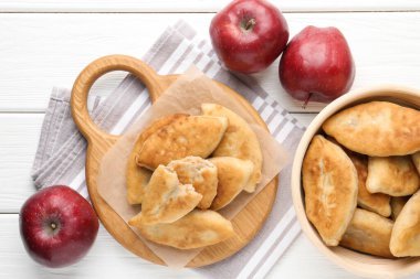 Lezzetli kızarmış pirizky (doldurulmuş turtalar) ve beyaz ahşap masa üzerinde elmalar, düz yatıyordu.