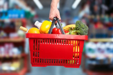 Süpermarkette elinde farklı gıda ürünleri olan bir adam var.