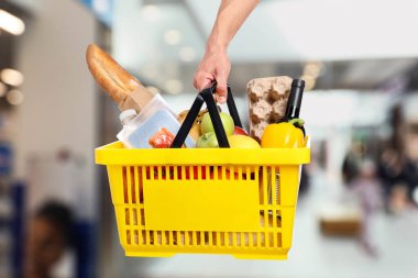 Süpermarkette elinde farklı gıda ürünleri olan bir adam var.