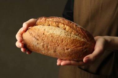 Gri arka planda taze ekmek somunu olan kadın, yakın plan.