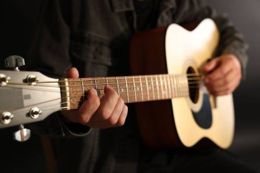 Siyah arkaplanda gitar çalan adam, yakın plan