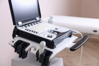 Modern ultrason makinesi ve klinikte muayene yatağı, yakın plan.