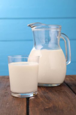 Açık mavi arka planda, ahşap masada taze süt, yakın plan.