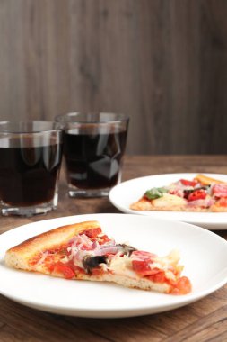 Ahşap masada servis edilen ince füme sosisli, lezzetli pizza dilimleri.