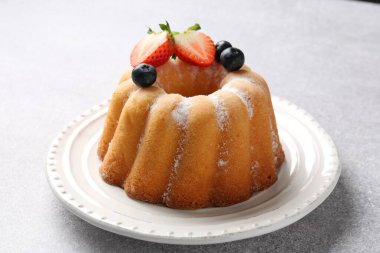 Açık gri masada pudra şekeri ve böğürtlenli Lezzetli kek, yakın plan.