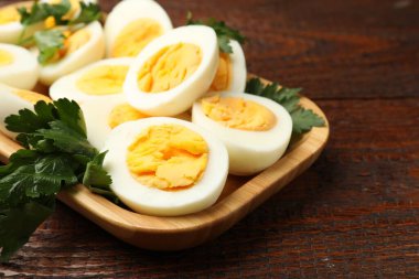 Ahşap masada haşlanmış yumurta ve maydanoz, yakın plan.