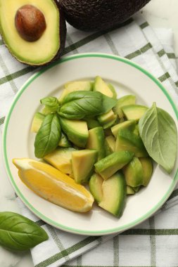 Lezzetli yeşil avokadolar, fesleğen ve limon masada, düz yerde.