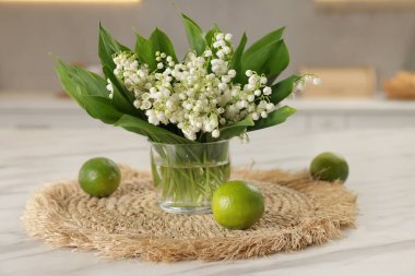 Güzel bir zambak buketi ve beyaz mermer masa üzerinde misket limonu, yakın plan.