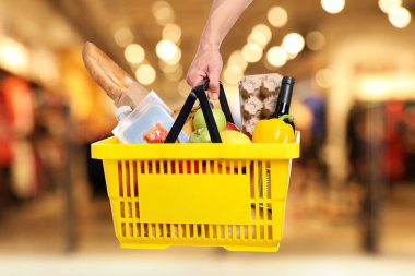 Süpermarkette elinde farklı gıda ürünleri olan bir adam var.