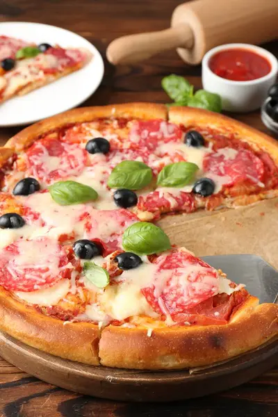 Lezzetli pizza ve malzemeler ahşap masada, yakın plan.