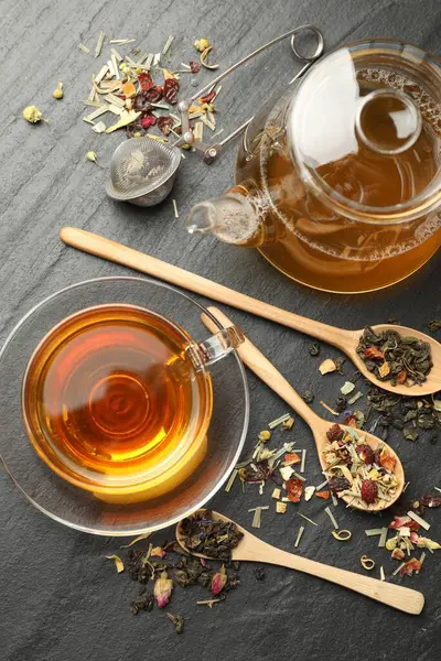 Lezzetli bitkisel çay ve kuru yapraklar siyah masada, düz yerde.
