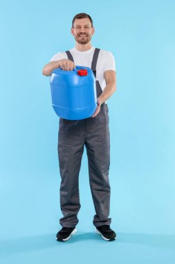 Açık mavi arka planda plastik kutu tutan adam.