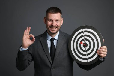 Hedef alınıyor. Ok ve dart tahtası olan adam gri arka planda iyi bir hareket gösteriyor.