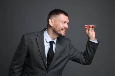 Hedef alınıyor. Gri arkaplanı hedefleyen dartlı adam.