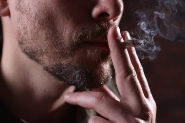 Arka planda sigara içen adam, yakın plan.