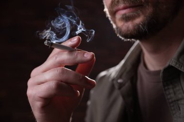 Arka planda sigara içen adam, yakın plan.