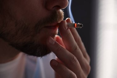 Arka planda sigara içen adam, yakın plan.