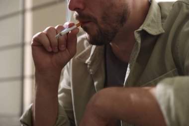 Arka planda sigara içen adam, yakın plan.